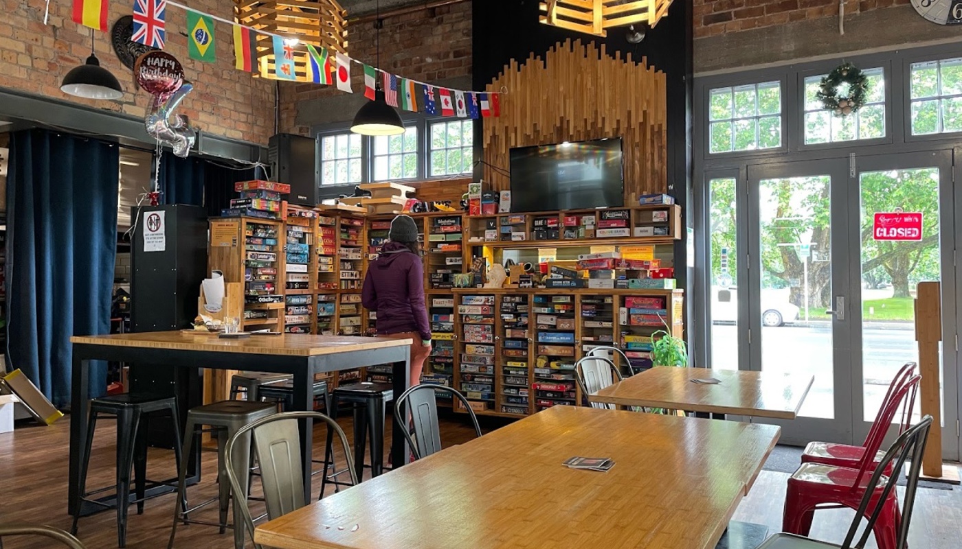 Interior photo of Dice & Fork featuring tables and the boardgame wall.