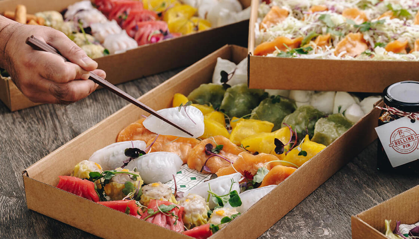 A box of dumplings with a chopstick picking up one to eat