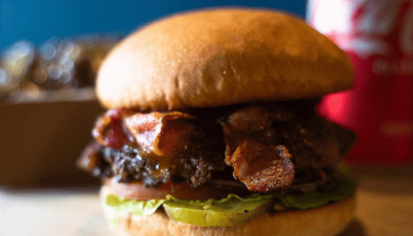 A single smashed beef burger on a wooden board.
