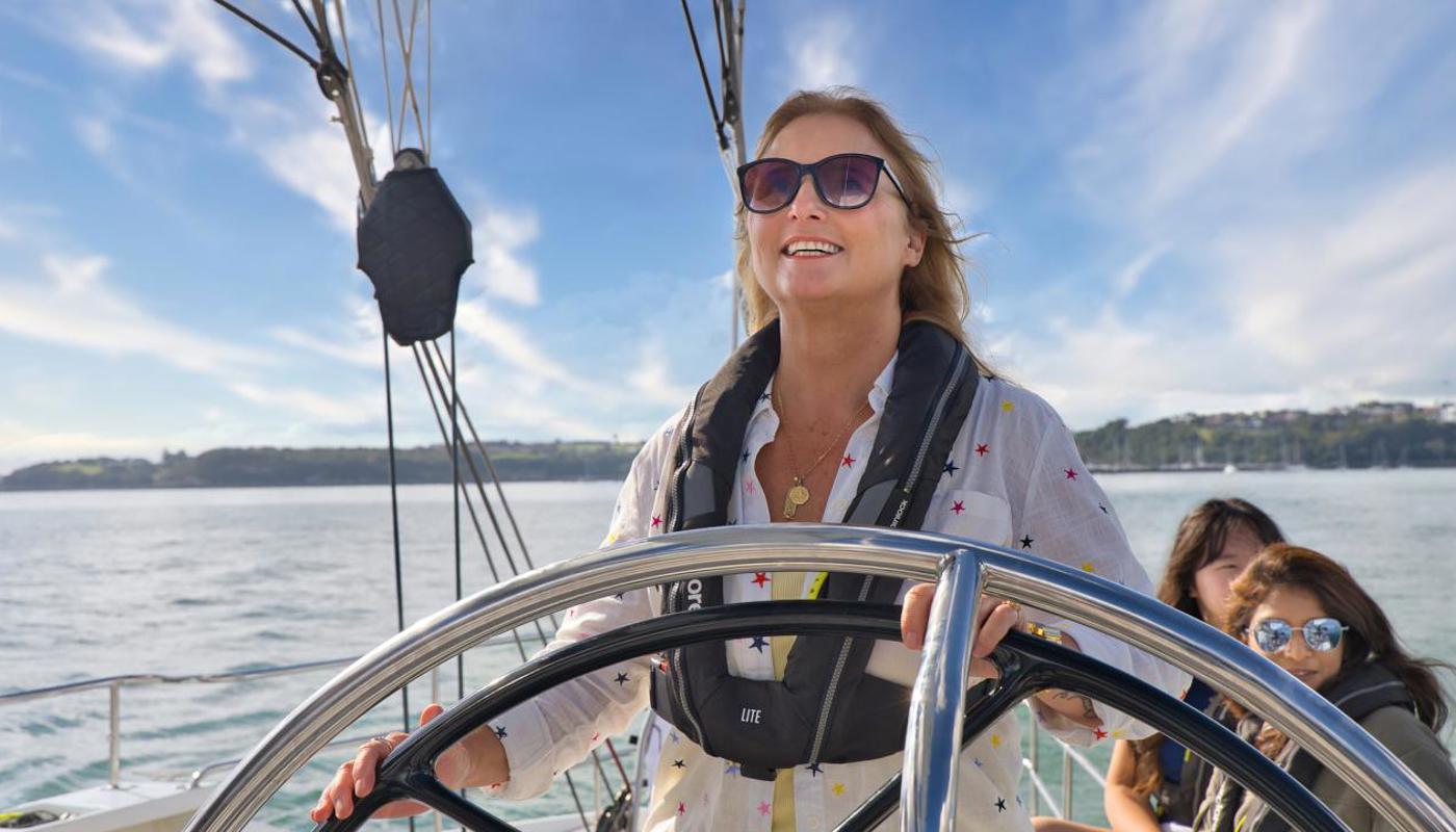Passenger takes the help onboard an America's Cup Sailing Experience.