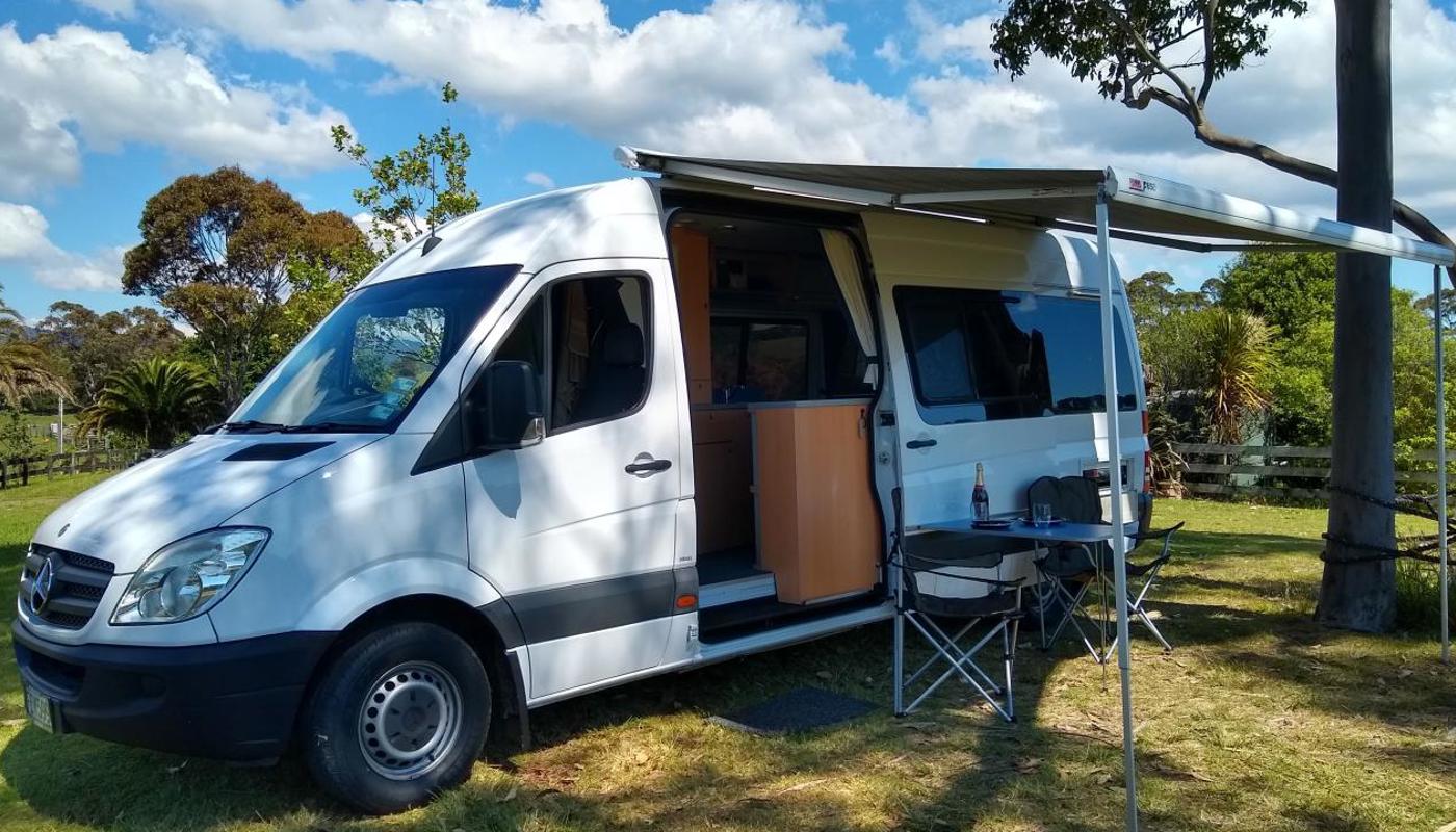 Mercedes Sprinter 2 berth with awning and outdoor chairs and table.